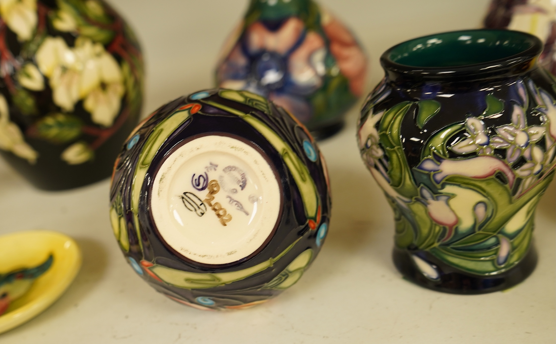 A collection of modern Moorcroft to include a mountain gold pattern vase, two pin dishes and a Hibiscus pattern candlestick, largest 20cm high